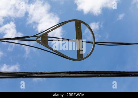 Snowshoe fiber optic radius limiter alongside overhead power lines against blue sky with clouds, horizontal aspect Stock Photo