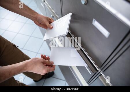 Close-up Of Man's Hand Inserting Letters In Mailbox Stock Photo