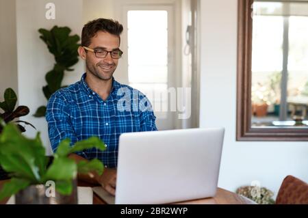 Smiling man working from home with a laptop Stock Photo