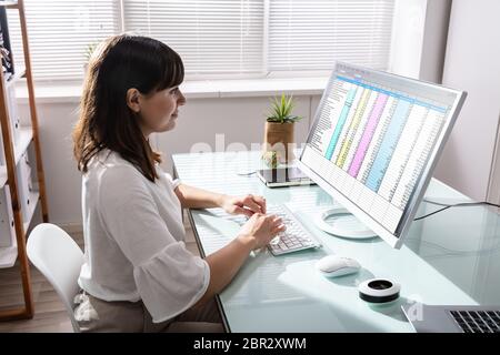 Side View Of Businesswoman's Hand Analyzing Data On Computer Over Desk Stock Photo