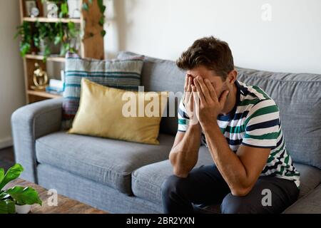 Distraught man sitting with his head in his hands Stock Photo