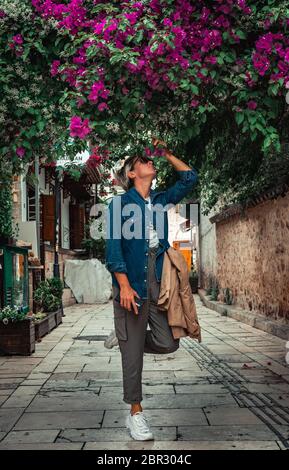 Pretty adult woman smelling spring flowers in streets of Antalya’s old town.Old town in city centrum is a must see place for tourists. Stock Photo