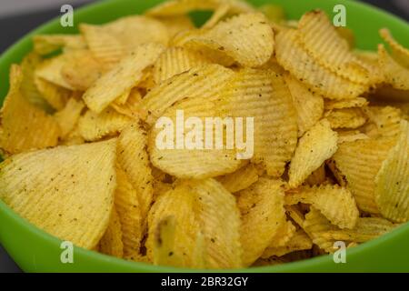crispy potato chips in a green cup close-up. corrugated potato chips Stock Photo