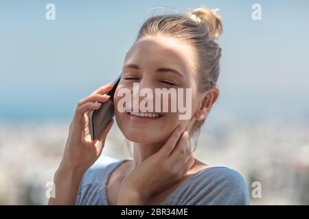 Portrait of a happy cheerful girl on the phone laughs with best friend, talking about something fun, enjoying good times, socializing Stock Photo