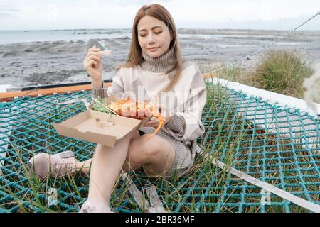 Beautiful asian woman holding a lobster claw or crayfish outdoor with beautiful sunlight on sailboat at the beach Kaikoura, New Zealand. Stock Photo