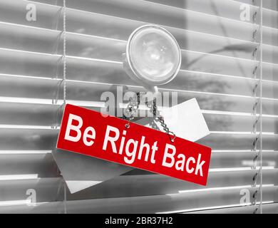 Sign saying 'Be right back' on a glass door with a white, closed venetian blind. It can be used for business concepts or backgrounds. Stock Photo