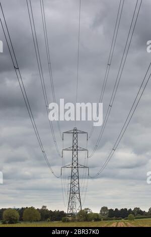 Isolated electricity pylon standing in UK farmer's countryside field. Stock Photo