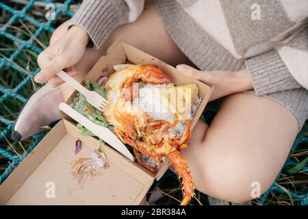 Beautiful asian woman holding a lobster claw or crayfish outdoor with beautiful sunlight on sailboat at the beach Kaikoura, New Zealand. Stock Photo