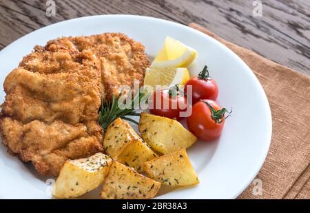 Portion of schnitzel with garnish on the wooden table Stock Photo