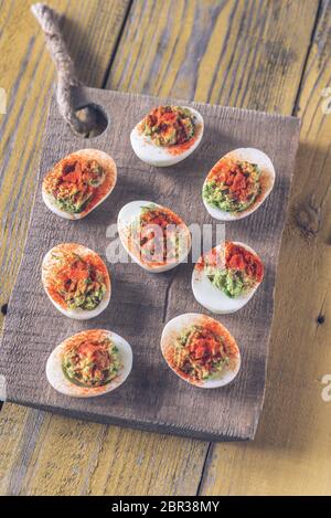 Guacamole and bacon deviled eggs on cutting board Stock Photo