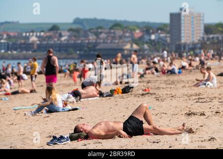 Portobello, Scotland, UK. 20 May 2020. Hot sunny weather brought out large crowds to Portobello beach today. Lockdown discipline seems to be a thing of the past with families and friends hitting the sand. A heavier than normal police presence had little visible effect since the public returned to the sand after the police walked away.  Iain Masterton/Alamy Live News Stock Photo