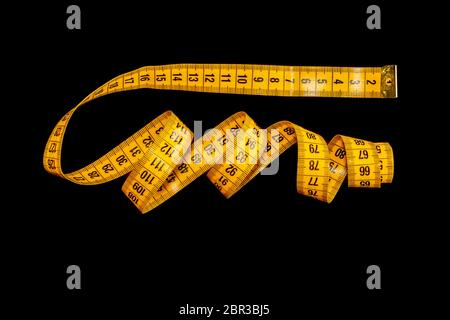 Yellow measuring tape isolated on a black background. Stock Photo