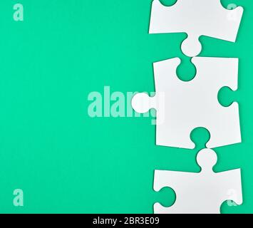 blank white big puzzles on green background, copy space Stock Photo