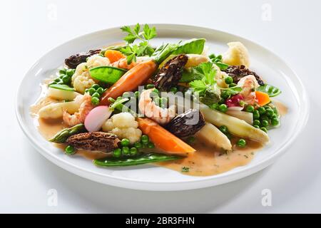 Gourmet hot salad with morel mushrooms and fresh white asparagus spears served with mangetout peas, carrots, cauliflower and fresh coriander Stock Photo