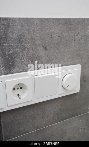 Light switch on the gray textured wall, light switch concrete wall close-up Stock Photo