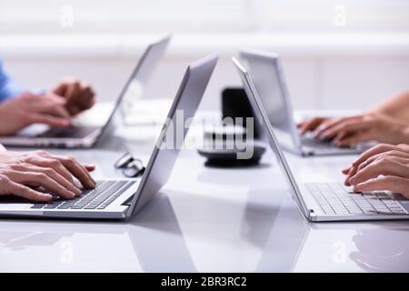 Close-up Of A Businessman Hands On Laptops Keypads On Desk In Office Stock Photo