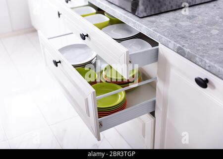 Set Of Different Clean Plates Inside The Opened Drawers In Kitchen Stock Photo