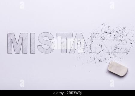Close-up Of Pencil Eraser Erasing Mistake Word On White Paper Stock Photo