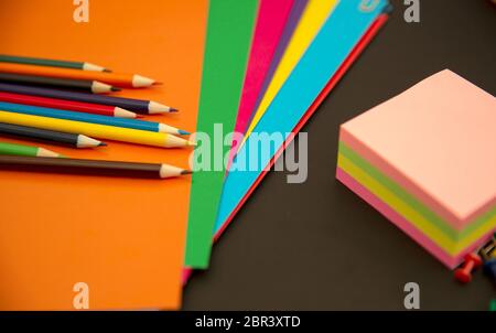 Pencils, multi-colored paper and paper clips on a black background Stock Photo