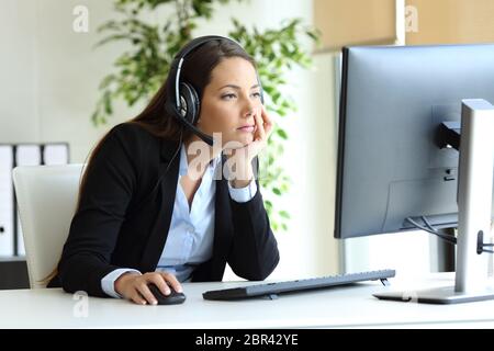 Bored telemarketer working checking desktop computer at office Stock Photo