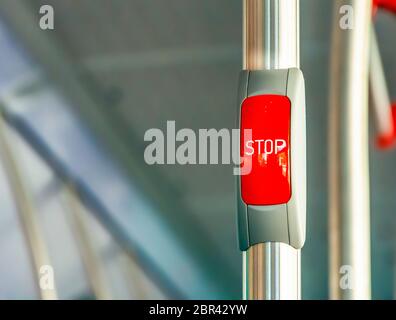 Red stop button on the metal handrail of a bus. Public transport. Public transportation Stock Photo