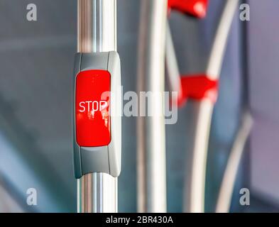 Red stop button on the metal handrail of a bus. Public transport. Public transportation Stock Photo