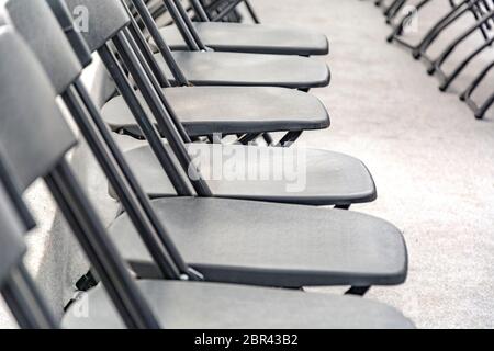 Rows of black folding chairs empty in a conference room Stock Photo