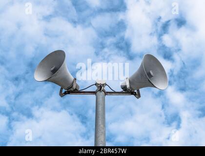 Old loud speakers isolated on the blue sky background with white clouds. Stock Photo