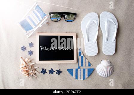 Flat Lay Of Chalkboard On Sandy Background. Sunny Summer Decoration As Holiday Greeting Card. Sand And Beach Environment. French Text Bienvenue Means Stock Photo