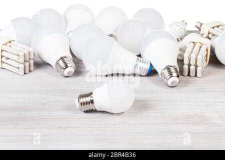 white LED bulb lights and fluorescent tube lamps on gray wooden board and white background Stock Photo