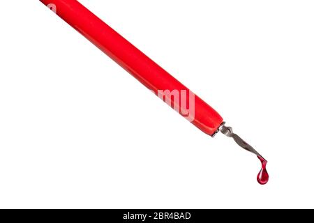 side view of ink drop dripping from tip of nib of red dip pen close up isolated on white background Stock Photo