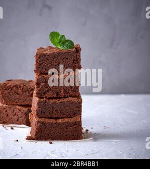 pile of square slices of baked brownie pie on a white surface, close up Stock Photo