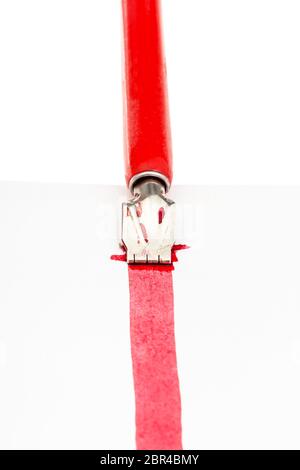 red dip pen draws a red line on sheet of paper by wide nib close up isolated on white background Stock Photo