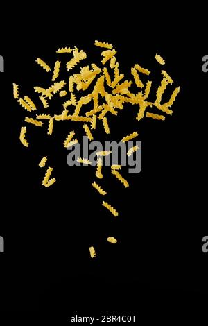 Italian flying raw pasta isolated on black background. macaroni fusilli falling. Stock Photo