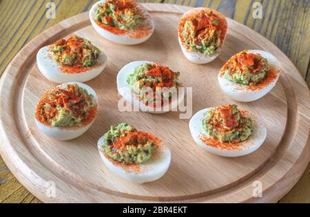 Guacamole and bacon deviled eggs on cutting board Stock Photo
