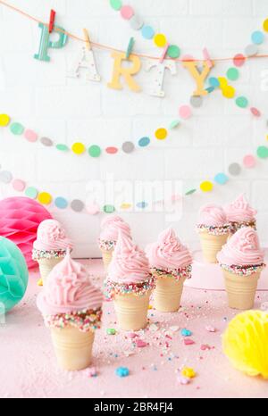 Pink soft serve ice cream with colorful sprinkles in little waffle cups Stock Photo
