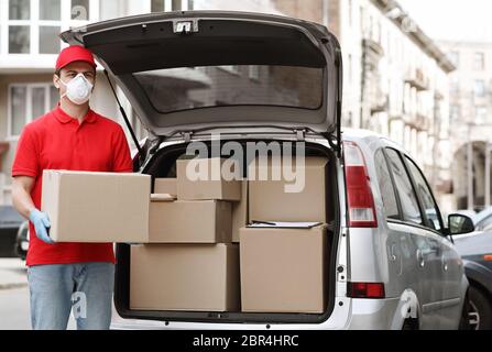 Many orders, a lot of deliveries concept. Courier holds big parcel near the car Stock Photo