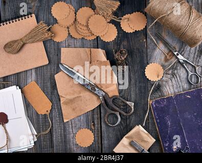 coil of brown rope, paper tags and old scissors on a gray wooden background, objects for making handicrafts Stock Photo