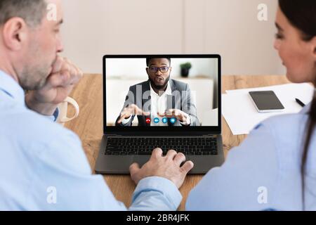 Workers having discussion during video call with colleague Stock Photo