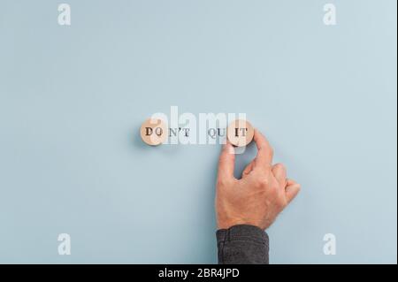 Male hand making a Don't quit sign in combination of handwriting and letters on wooden cut circles that also reads a Do it message. Stock Photo