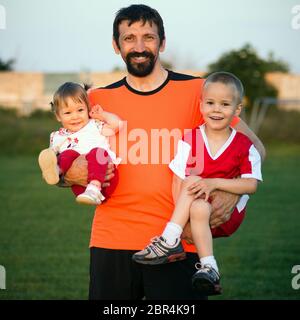 Family portrait of happy family with uncle and children outdoors. Uncle is holding in his hands the boy and the baby girl. Stock Photo