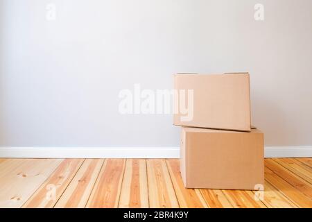 two cardboard boxes in empty room with wall background and copy space, moving in new flat concept mockup Stock Photo