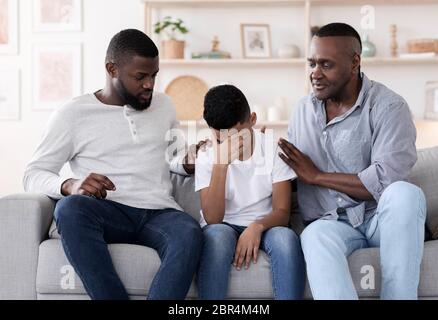 Family Support. Black father and grandfather comforting upset little boy at home Stock Photo
