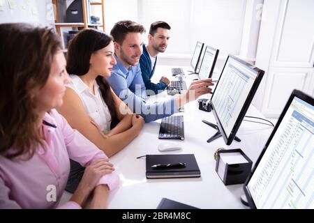 Young Businesspeople Analyzing Gantt Chart On Computer At Workplace Stock Photo