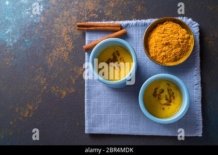 Golden turmeric latte milk made with turmeric and other spices, on wooden background. Healthy drink. Top view. Stock Photo