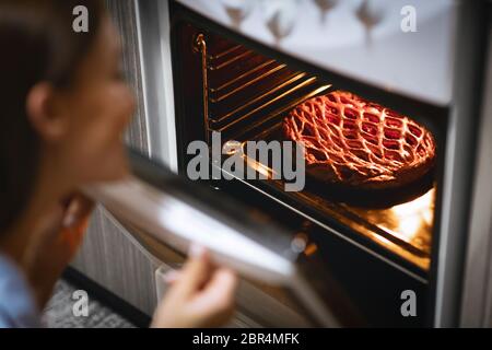 Fresh sweet pie in open oven , housewife enjoying baking Stock Photo