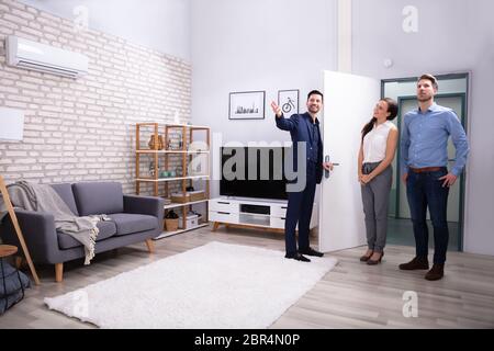 Happy Realtor Showing New Modern House To Customers Stock Photo