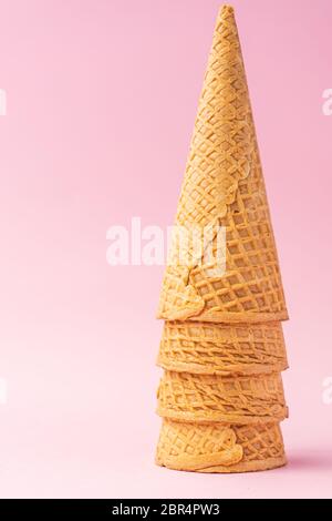 Three wheat flour ice cream cones upside down one on top of the other on a pink background. Summer concept. Stock Photo