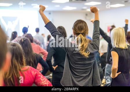 Life coaching symposium. Speaker giving interactive motivational speech at business workshop. Rear view of unrecognizable participants feeling empower Stock Photo
