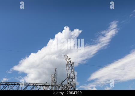 Steel metal electrical power trusses against a beautiful blue sky with clouds, horizontal aspect Stock Photo